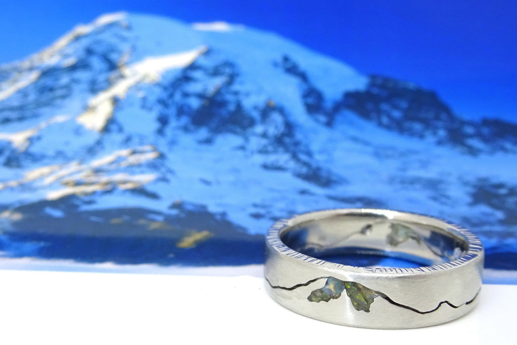 Close-up of platinum Rainier Summit ring featuring vibrant black opal inlay and detailed mountain silhouette design.