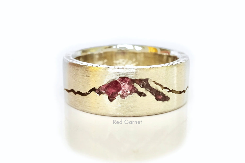 Close-up of a white gold Rainier Summit ring featuring red garnet inlay and detailed mountain silhouette design.